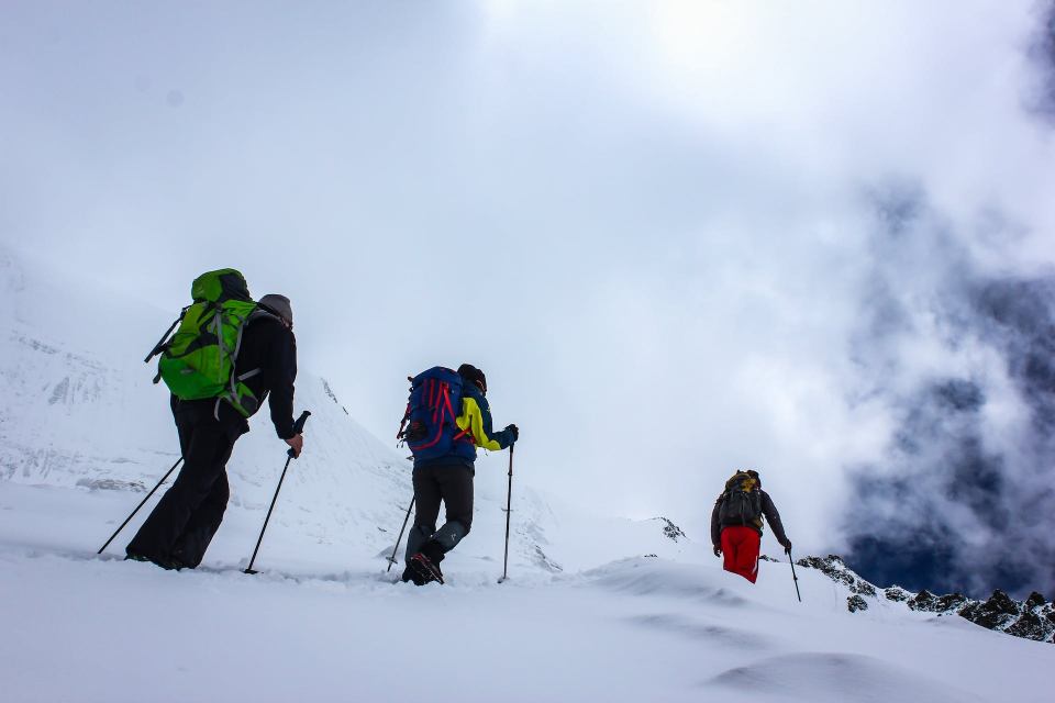 2. Hiking vs. trekking, in materie de echipament necesar - trei persoane cu rucascuri si bete de trekking, pe munte inzapezit